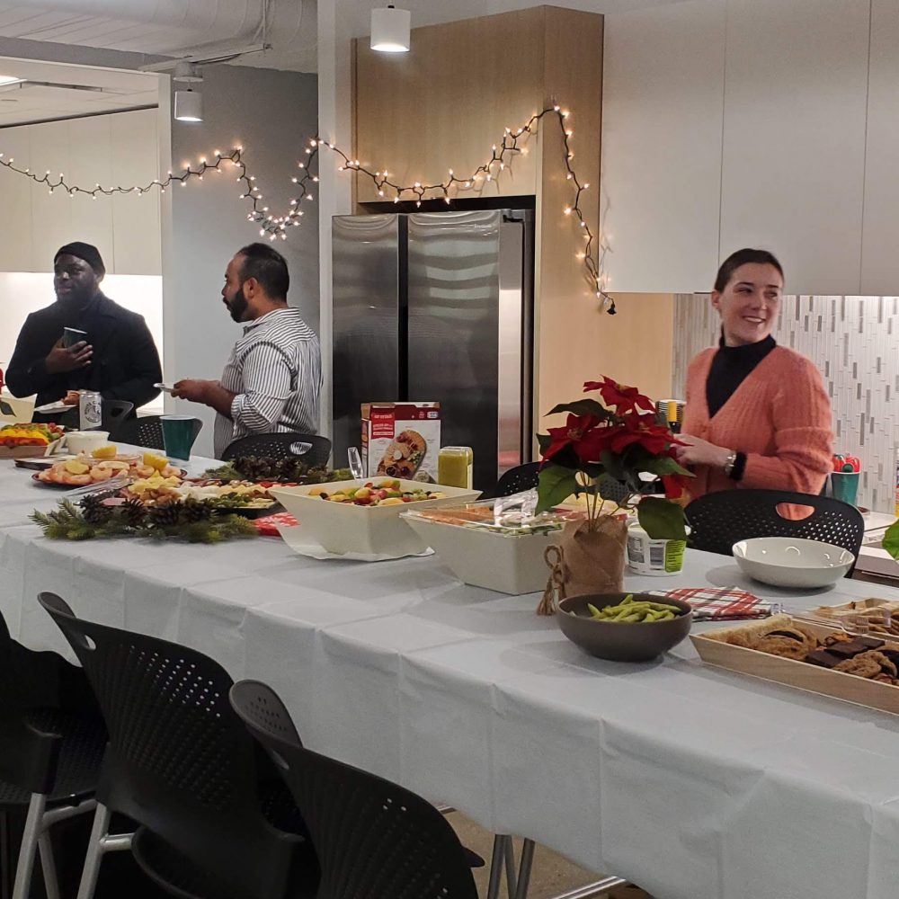 Several people in an office kitchen preparing for a holiday party