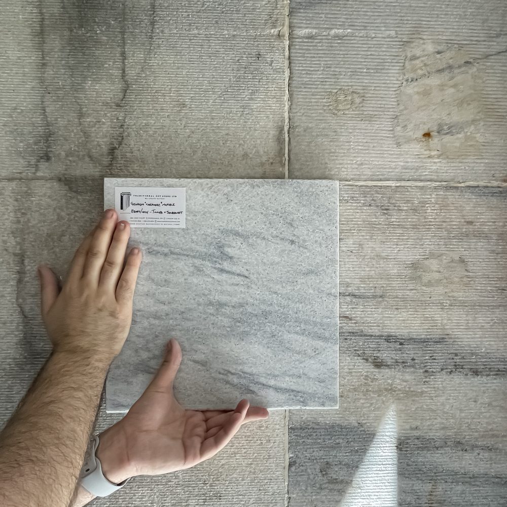 An architect holds up a marble sample to a surrounding wall to evaluate stone matching